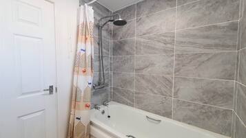 Ein Badezimmer mit einer Badewanne, Dusche und grauen Marmorfliesen.