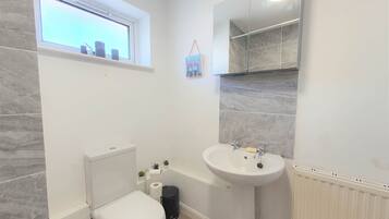 Ein Badezimmer mit Toilette, Waschbecken und Fenster.