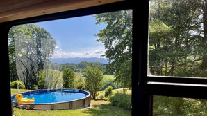 Vista de un jardín trasero con piscina, rodeado de árboles y césped.