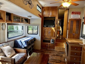 A compact RV interior with a kitchenette, a dining area, and a sleeping space.