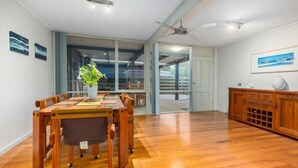 A dining area with a wooden table and chairs, a vase with a plant, and a wooden cabinet with drawers.