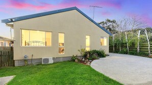 A modern single-story house with a flat roof, large windows, and a well-maintained lawn.