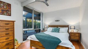 A bedroom with a bed, wooden nightstands, a ceiling fan, a window, and a dresser.