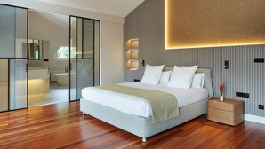 A modern bedroom with a large bed, a wooden floor, a sliding door, and a built-in shelf unit. - Villa Jaizubia Golf by FeelFree Rentals (Hondarribia)