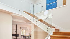 A modern staircase with glass railings and wooden steps leading to an upper level. - Villa Jaizubia Golf by FeelFree Rentals (Hondarribia)