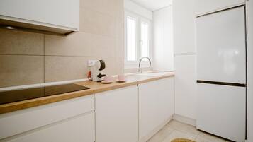 Una cocina moderna con armarios blancos, encimera de madera, horno integrado y un fregadero.
