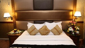 A hotel room with a large bed, two bedside tables with lamps, and a decorative headboard. - ABJAD CROWN HOTEL (Dubai)