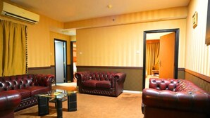 A hotel room with a red leather sofa set, a glass coffee table, and a carpeted floor. - ABJAD CROWN HOTEL (Dubai)