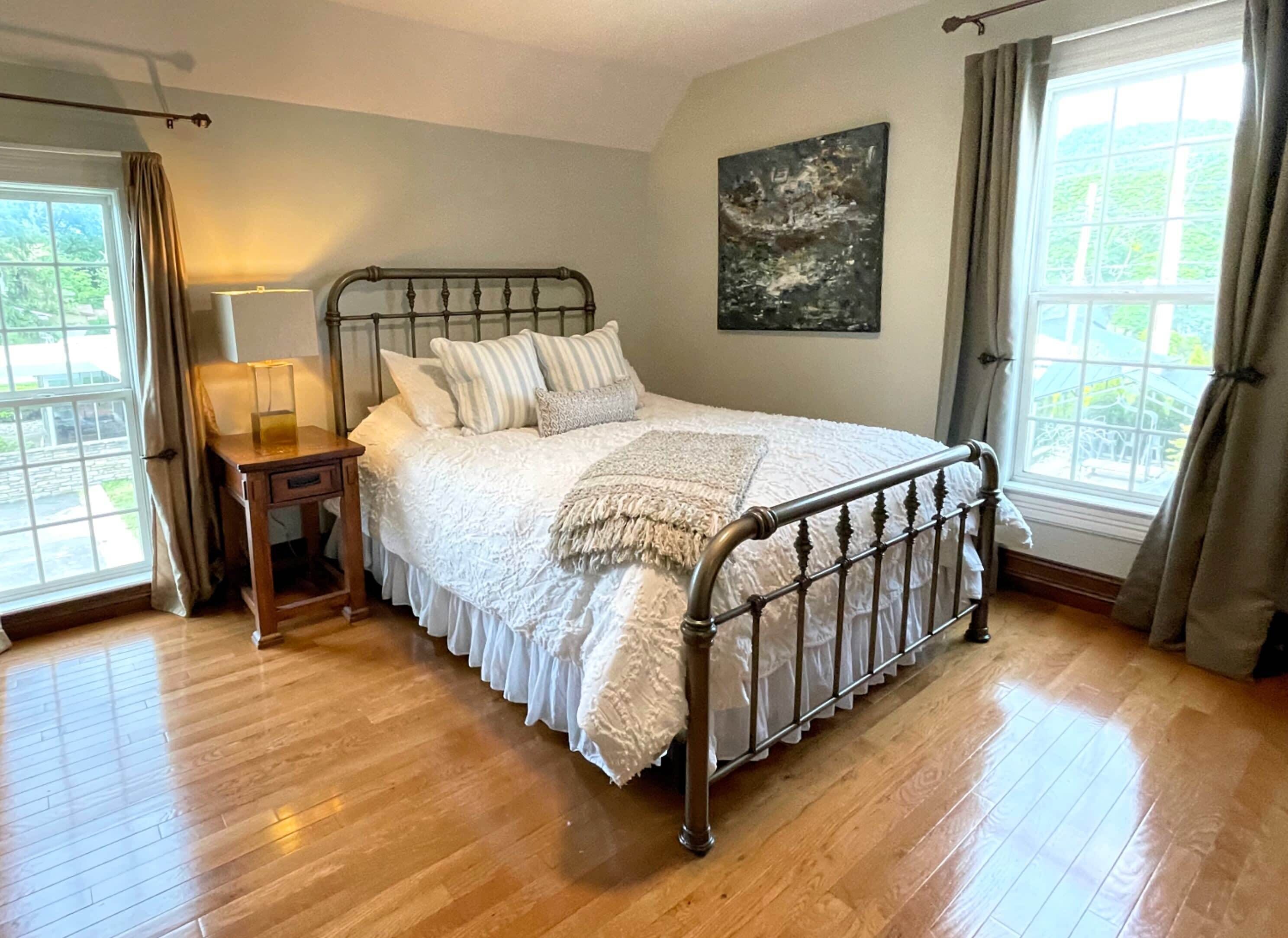 A bedroom with a wooden bed, a nightstand, a lamp, and a painting on the wall.
