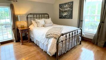 A bedroom with a wooden bed, a nightstand, a lamp, and a painting on the wall.
