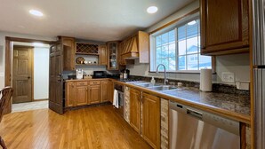 A kitchen with wooden cabinets, a stainless steel refrigerator, a dishwasher, and a window providing natural light.