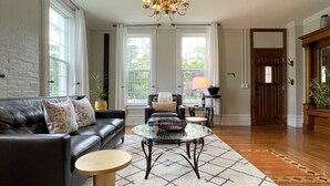 A living room with a leather sofa, a glass coffee table, and a patterned rug.