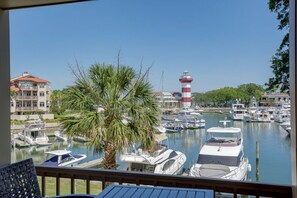Un puerto deportivo con barcos amarrados, un faro y una palmera en primer plano.