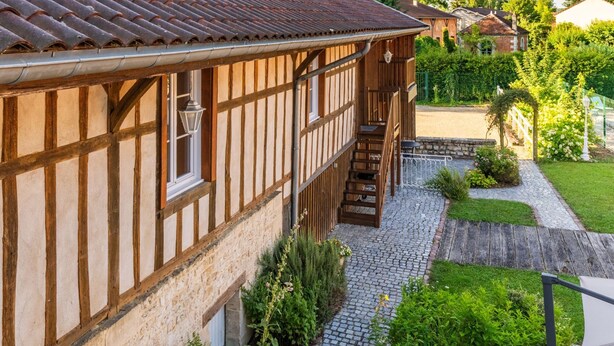 A traditional half-timbered house with a stone staircase leading to a wooden deck.