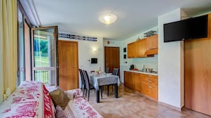 A compact living space with a dining area, kitchenette, and a sofa with patterned bedding. - La Marmotta Ski In/ski out - Studio With Terrace (Bardonecchia)