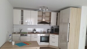 Una cocina moderna con armarios blancos, encimera de madera y horno empotrado.