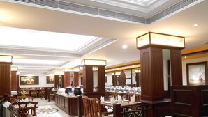 A hotel dining area with multiple tables, chairs, and a central buffet station. - THE SOUTH PARK (Thiruvananthapuram)