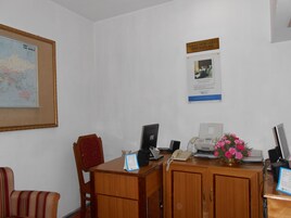 A reception desk with a computer, phone, and a framed world map.