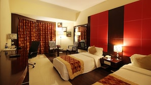 A hotel room with two beds, a desk, a chair, and a nightstand with a lamp. - THE SOUTH PARK (Thiruvananthapuram)