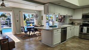 A modern kitchen with white cabinets, a stainless steel oven, and a dining area with a pool view. - Outdoor lovers dream home- Pool, outdoor kitchen, private dock, and so much more (New Port Richey)