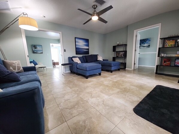 A spacious living room with a blue sofa set, a floor lamp, and a ceiling fan. - Outdoor lovers dream home- Pool, outdoor kitchen, private dock, and so much more (New Port Richey)