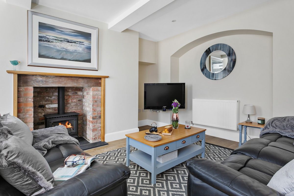 Una sala de estar con chimenea, televisor y sofá.