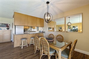 Una cucina moderna con mobili in legno, un tavolo da pranzo in vetro, sedie in vimini e un lampadario.