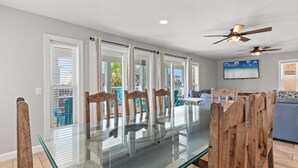 A dining area with a glass-top table, wooden chairs, and a ceiling fan. - Beach House - Gulf Dream (Panama City Beach)