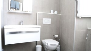 A modern bathroom with a white vanity, toilet, and a shower area. - Palazzo Leonardo 1 (Scicli)
