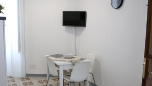 A small dining area with a table and chairs, a wall-mounted TV, and a patterned floor. - Palazzo Leonardo 1 (Scicli)