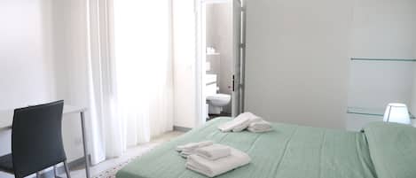 Una camera da letto con un letto, una sedia, un bagno e una mensola in vetro.