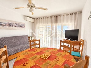 A living room with a round table, chairs, a sofa, a television, and a ceiling fan. - 160B (Cambrils)