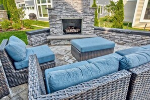 A stone fireplace surrounded by wicker furniture with blue cushions. - Coastal Club Community * 19079 * w/ Resort-Style Amenities* 6 Br (Lewes)