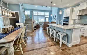 A kitchen with a central island, bar stools, a dining table with chairs, and a staircase leading to another level. - Coastal Club Community * 19079 * w/ Resort-Style Amenities* 6 Br (Lewes)