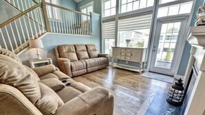 A spacious living room with a large sectional sofa, a fireplace, and a view through large windows.