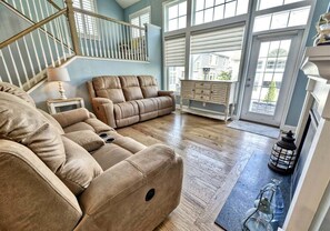 A spacious living room with a large sectional sofa, a fireplace, and a view through large windows. - Coastal Club Community * 19079 * w/ Resort-Style Amenities* 6 Br (Lewes)