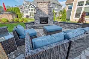 An outdoor patio with wicker furniture, a stone fireplace, and a view of a residential area. - Coastal Club Community * 19079 * w/ Resort-Style Amenities* 6 Br (Lewes)