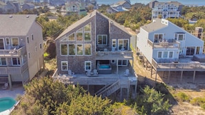 Ein zweistöckiges Haus mit einer großen Terrasse, einem Whirlpool und Blick aufs Meer.