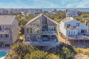 A two-story house with a large deck, a hot tub, and a view of the ocean. - Stunning Oceanfront Home with Hot Tub, Grill, and Stellar Ocean Views (Avon)