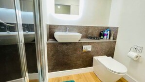 Une salle de bain moderne avec une douche à l’italienne en verre, un lavabo blanc et des toilettes.