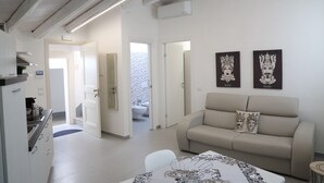 A modern living room with a sofa, a dining table, and artwork on the wall.