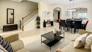 Amplia sala de estar con escalera, comedor y cocina.