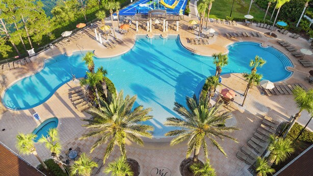 Un resort con varias piscinas, palmeras y tumbonas.