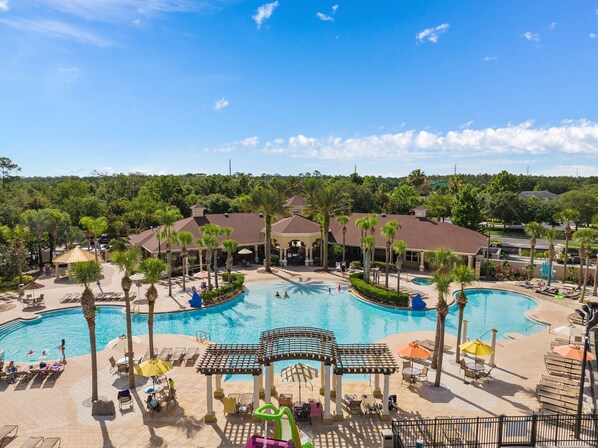 Een resort met een groot centraal zwembad, verschillende kleinere zwembaden en een overdekt gedeelte met parasols en ligbedden.
