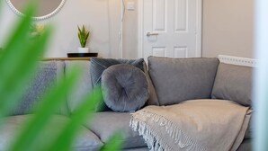 A living room with a sofa, a lamp, a door, and a wall-mounted mirror.