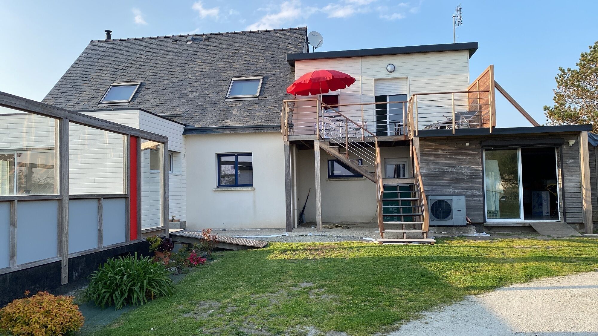 A two-story house with a visible staircase, a satellite dish, and a small garden area.