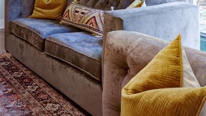 A cozy living room with a sofa, a patterned rug, and a stained glass window.