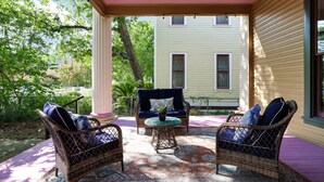 A covered porch with wicker furniture and a patterned rug.