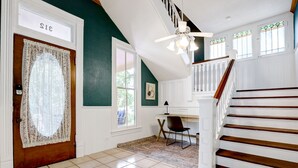 A spacious hallway with a wooden door labeled "S13", a desk with a chair, and a staircase with white railings.