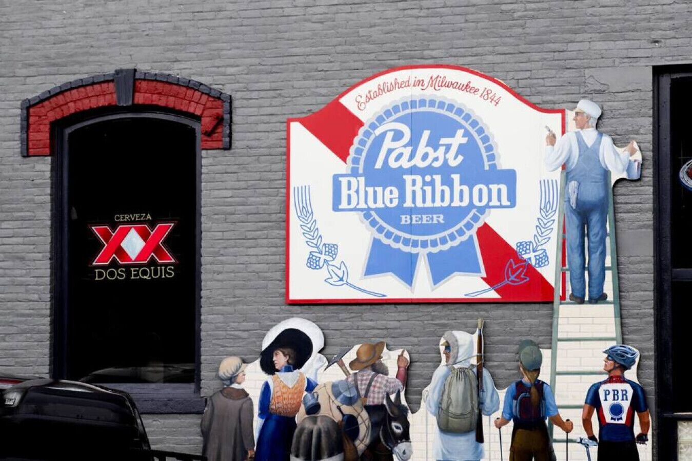 A building with a large sign for 'Pabst Blue Ribbon Beer' and a smaller sign for 'Cerveza Dos Equis'.